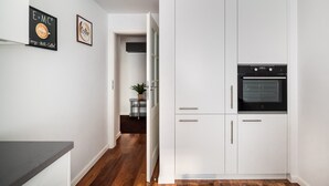 Eine moderne Küche mit weißen Schränken, einem eingebauten Backofen und einer Arbeitsplatte.