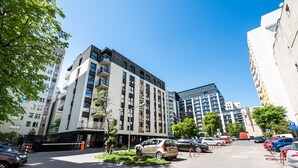 Moderni, useassa kerroksessa oleva rakennus, jossa on parkkipaikka, ja sen yllä näkyy kirkas, sininen taivas.