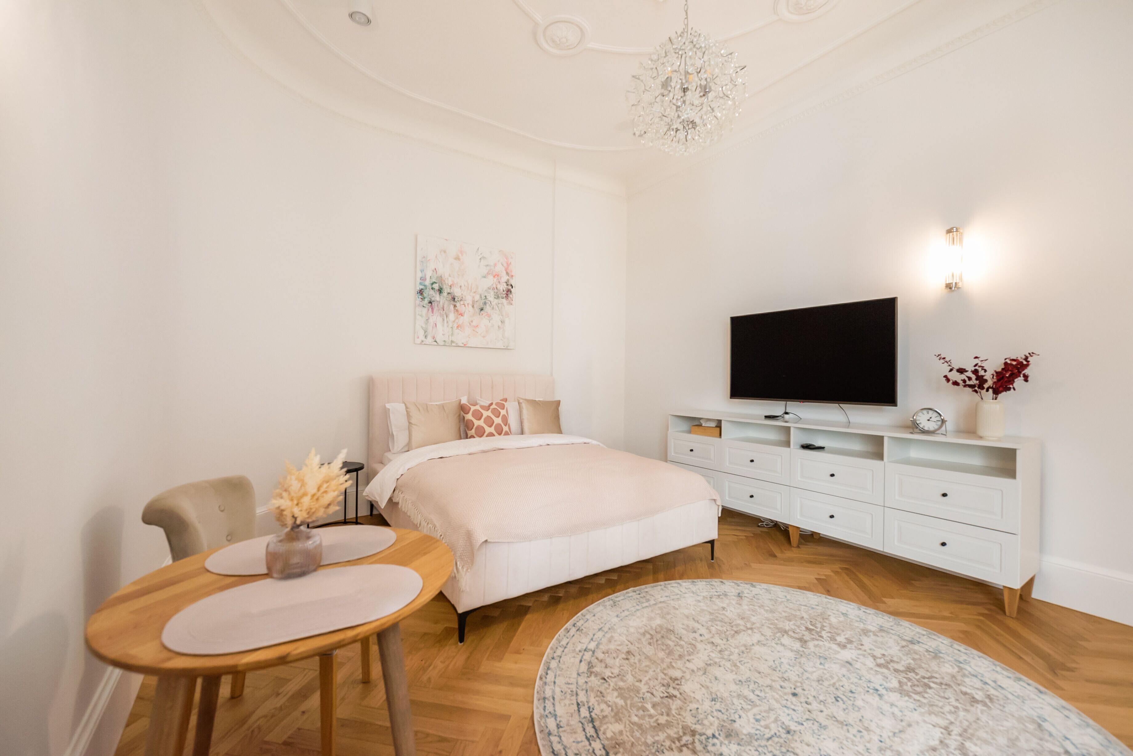 Ein Schlafzimmer mit einem Bett, einem Fernseher, einem Schreibtisch und einer Kronleuchter.