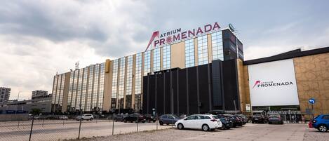 Un hotel grande con un llamativo letrero Atrium Promenada, con fachada de vidrio moderna y varios espacios de estacionamiento al frente.