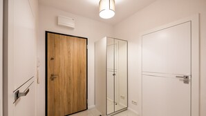 A modern room with a wooden door, a glass shower enclosure, and a white wardrobe.