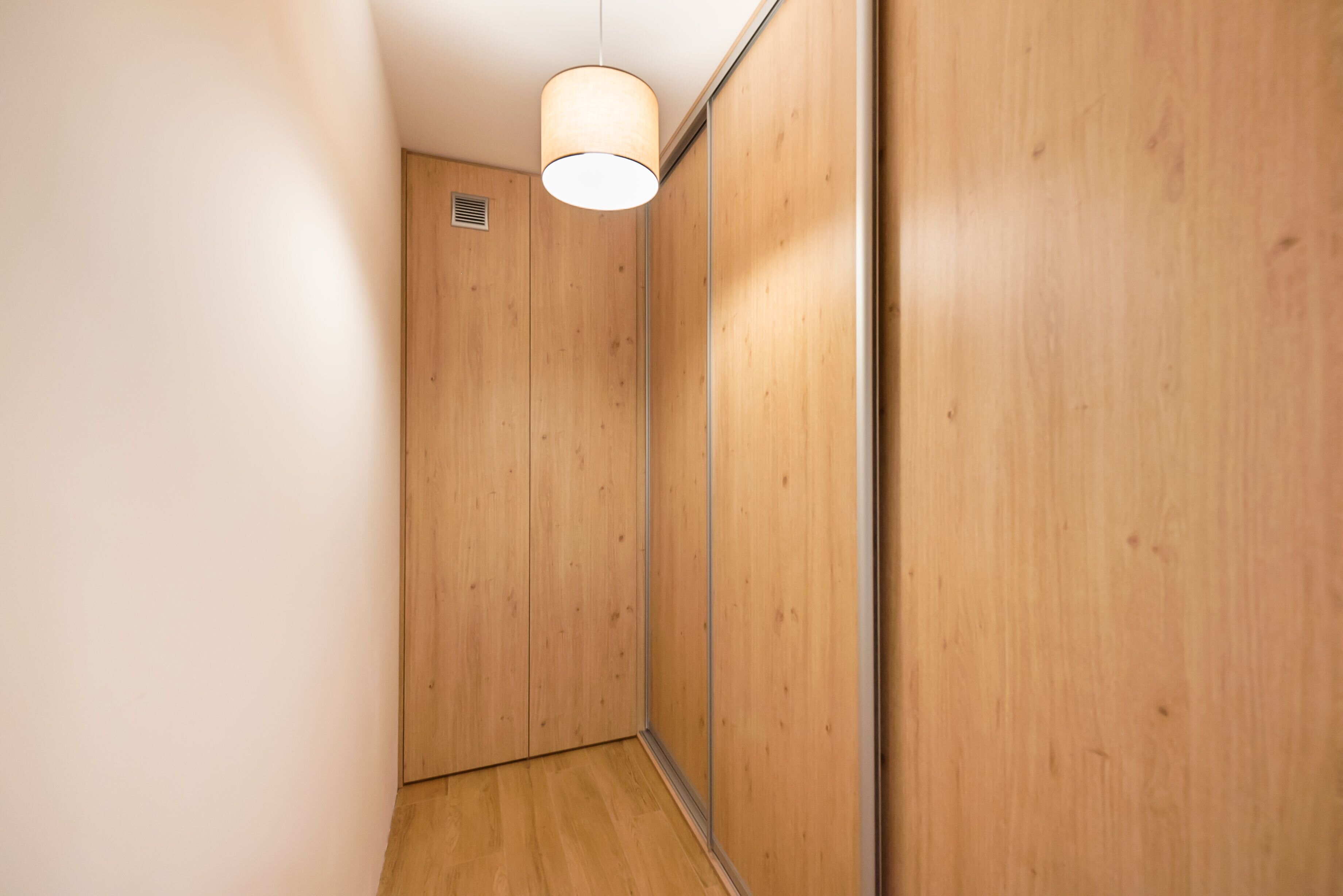 A narrow hallway with wooden walls and a ceiling light fixture.