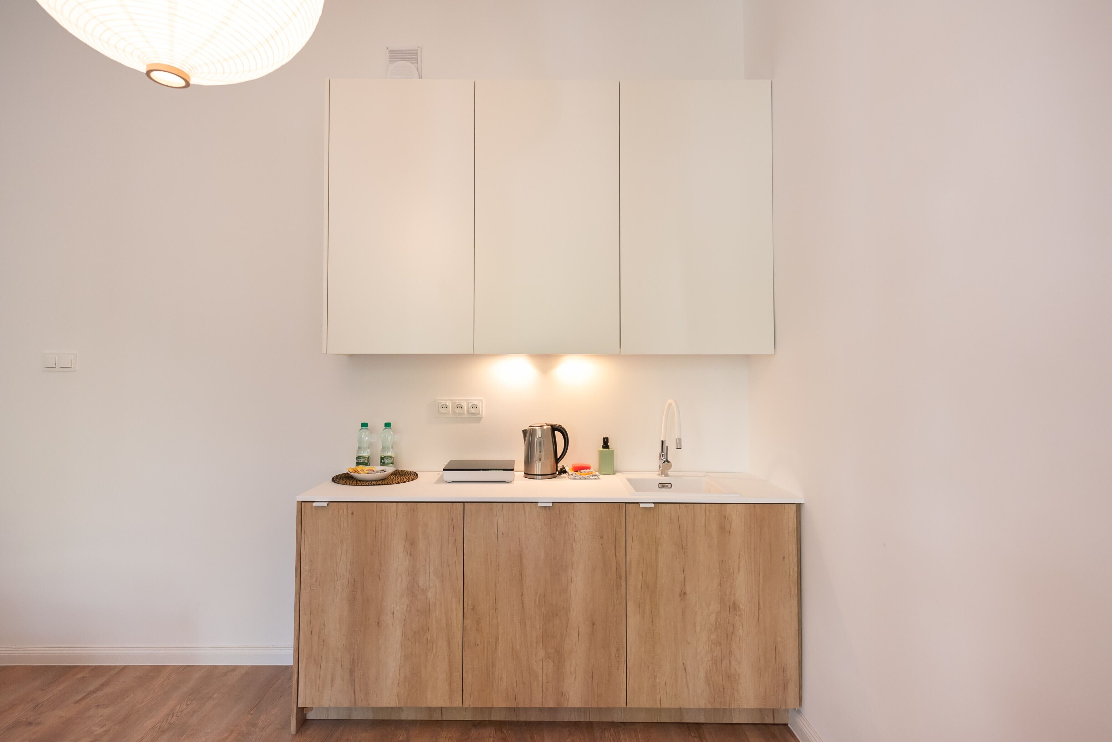 A modern kitchen with wooden cabinets, a white countertop, and a pendant light.