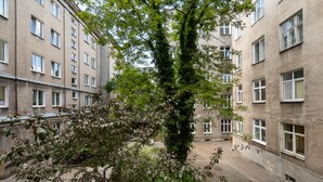 Sisäpiha, jossa on puu etualalla ja useita ikkunoita sisältävä rakennus taustalla.