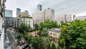 A cityscape with high-rise buildings, a parking lot, and green trees. - Ogród Saski Colored Studio (Warszawa)