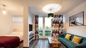 A modern living room with a bed, sofa, coffee table, and a TV. - Ogród Saski Colored Studio (Warszawa)