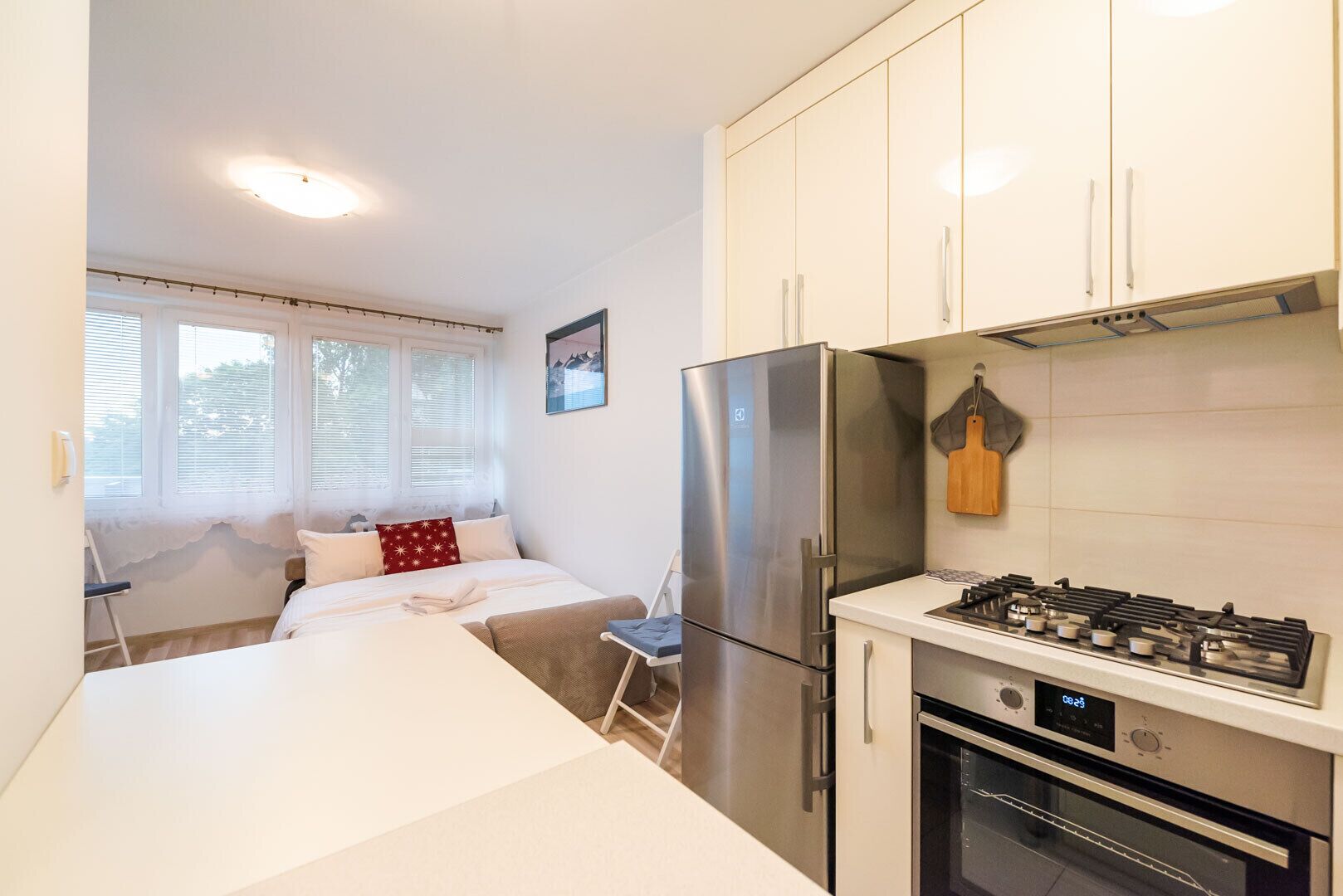 A compact kitchen with a refrigerator, stove, oven, and a small dining area with a chair and table.