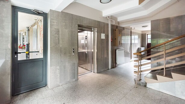 A modern interior with a staircase, elevator, and a door leading to an outdoor area. - Metro Plac Wilsona Etno Apartament (Warszawa)