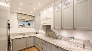 A kitchen with grey cabinets, a marble countertop, and a herringbone floor pattern. - Lovely Apartment In The Heart of Warsaw (Warszawa)