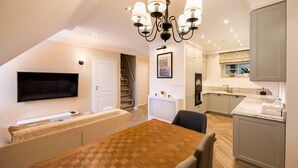 A modern kitchen with a dining area, a TV mounted on the wall, and a staircase leading to an upper level. - Lovely Apartment In The Heart of Warsaw (Warszawa)