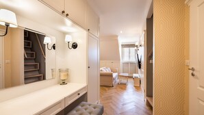 A modern bedroom with a large mirror, bedside table, bench, and a view of the living area. - Lovely Apartment In The Heart of Warsaw (Warszawa)