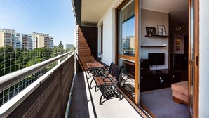 A balcony with a wooden table and two chairs, a TV, and a sofa. - Metro Wilanowska Homely Apartment (Warszawa)