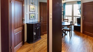 A hallway with wooden flooring, a glass partition, and a dining area with a table and chairs. - Metro Wilanowska Homely Apartment (Warszawa)
