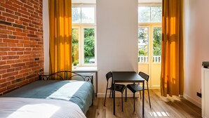 A room with a bed, a table with two chairs, and a window with curtains. - National Stadium Cosy Studio #2 (Warszawa)