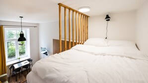 A bedroom with a large bed, a desk, and a chair near a window. - National Stadium Cosy Studio #3 (Warszawa)