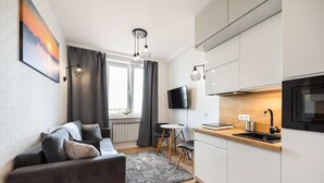 A modern living room with a grey sofa, a flat-screen TV, and a dining area with a small table and chairs.