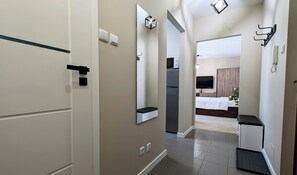 Een gang die leidt naar een slaapkamer met een bed, een televisie en een spiegel.