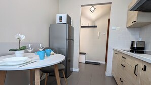 A compact kitchen with a refrigerator, microwave, and a coffee maker on the countertop. - Ursus Pleasant Apartment (Warszawa)
