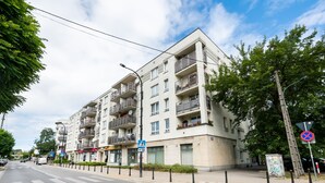 A multi-story residential building with balconies, a pedestrian crossing, and a no parking sign. - Ursus Pleasant Apartment (Warszawa)