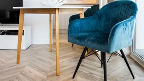 Eine moderne Küche mit Holzschränken, einer weißen Arbeitsplatte und einem blauen Stuhl.