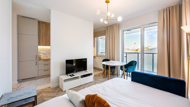 Ein modernes Hotelzimmer mit einem großen Bett, einem Fernseher, einem Essbereich mit Tisch und Stühlen sowie einem Balkon mit Aussicht.