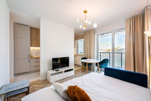 A modern hotel room with a large bed, a television, a dining area with a table and chairs, and a balcony with a view. - East Side of Warsaw Studio 111 (Warszawa)