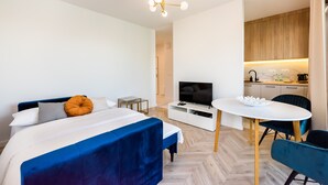 Ein modernes Hotelzimmer mit Bett, Fernseher, Esstisch und Küchenzeile.