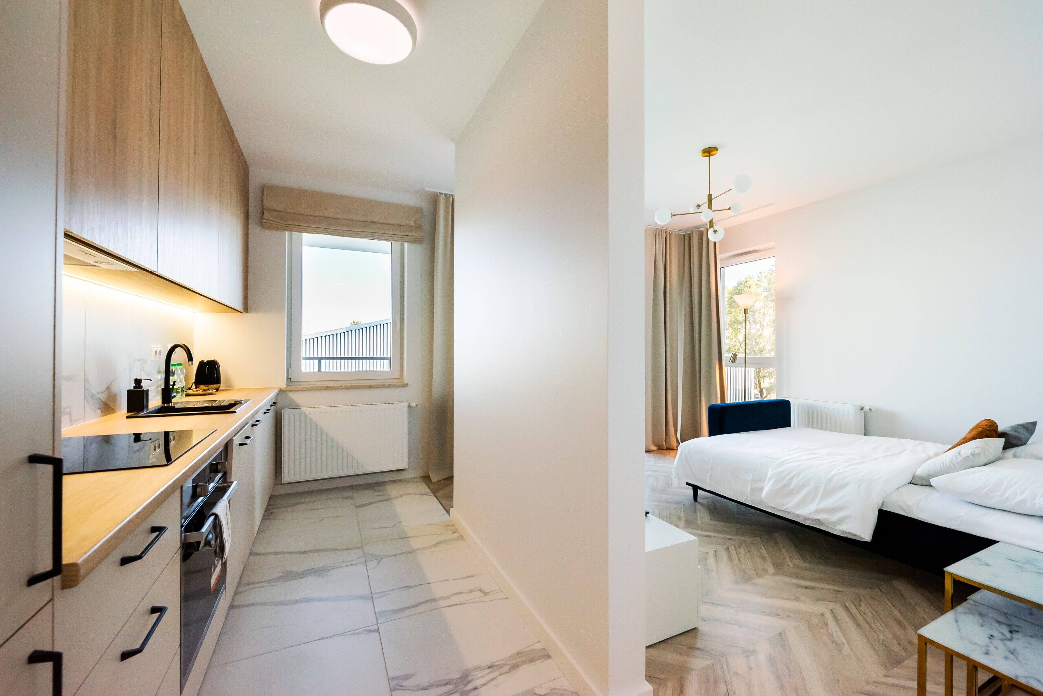 Quarto moderno com cama, mesa de cabeceira e vista para o exterior.