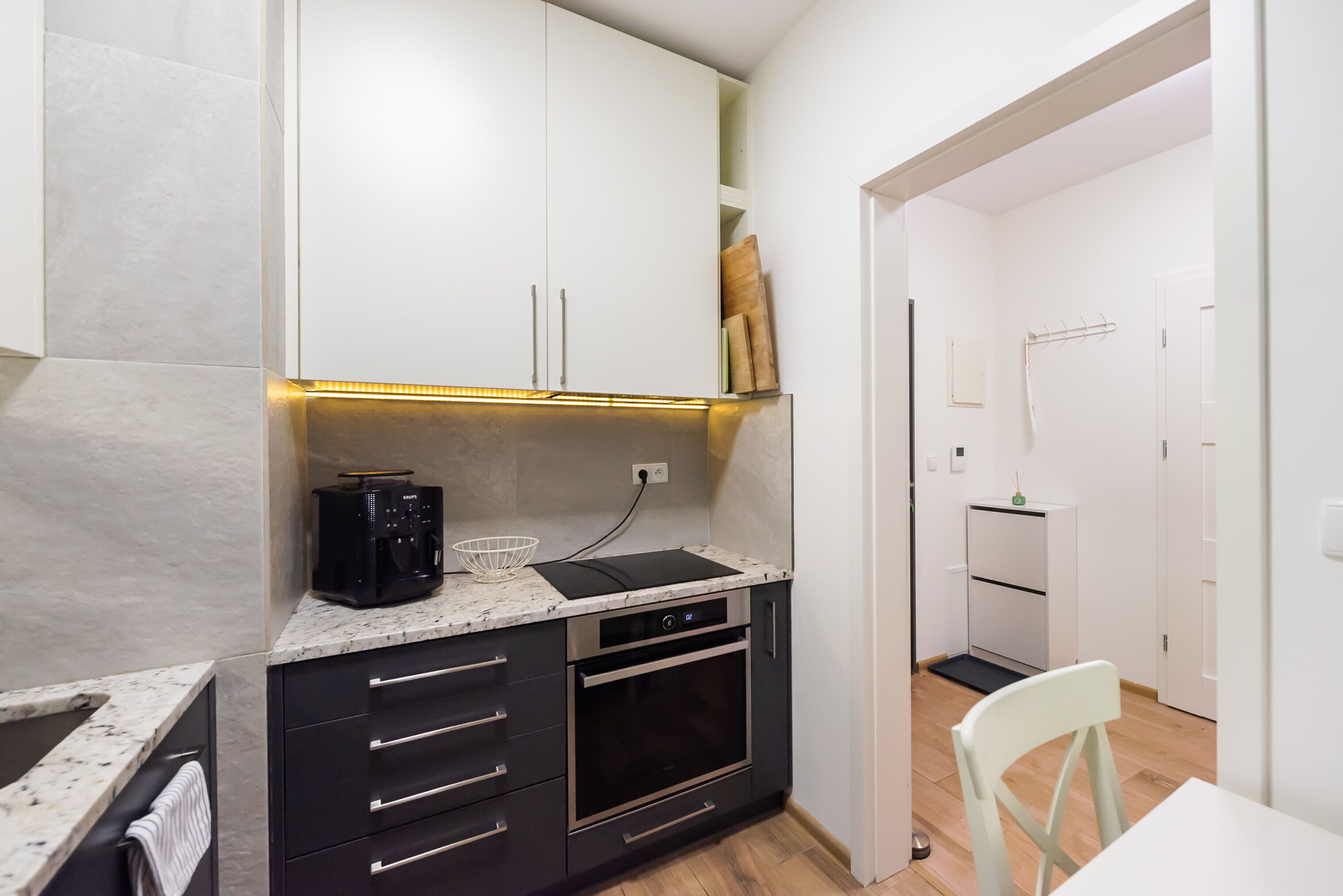 A compact kitchen with a built-in oven, a coffee maker, and a countertop with a sink.