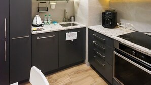 A modern kitchen with dark cabinets, a white countertop, a sink, a kettle, and a coffee maker. - Służewiec Comfort Zone Apartment (Warszawa)