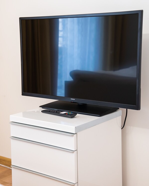 A flat-screen TV on a white cabinet with a remote control.