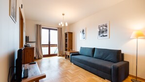 Ein modernes Wohnzimmer mit einer Couch, einem Fernseher, einer Lampe und Holzboden.