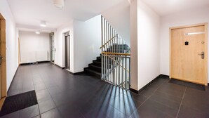 A modern hotel interior with a staircase, a wooden door, and a tiled floor. - Malborska Lovely Apartment (Warszawa)