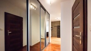 A hallway with a wooden floor, a sliding glass door, and a patterned wall. - Malborska Lovely Apartment (Warszawa)