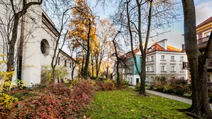 A courtyard with a building featuring a white facade and a red-tiled roof. - Mostowa Abdank Old Town Apartment (Warszawa)