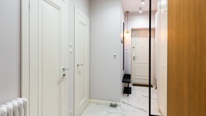 A hallway with white doors, a radiator, and a marble floor. - Mostowa Abdank Old Town Apartment (Warszawa)