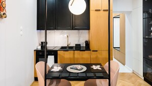 A modern kitchen with dark cabinets, a wooden countertop, and a hanging light fixture. - Mostowa Abdank Old Town Apartment (Warszawa)