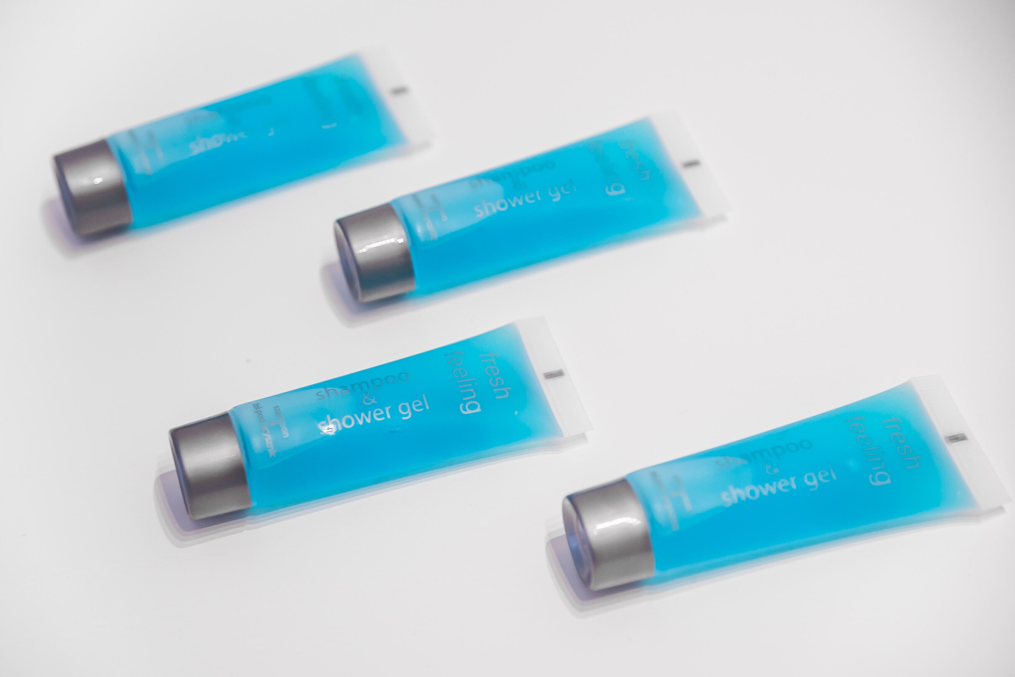 Four blue tubes of shower gel on a white surface.