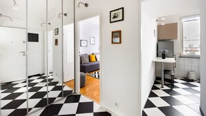 Eine moderne Wohnung mit einem Schachbrettmuster-Boden, einer sichtbaren Küchenzeile und einem Wohnzimmer mit Sofa und Kissen.