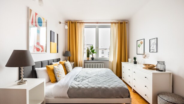 Ein modernes Schlafzimmer mit Bett, Nachttischen, einem Schminktisch und einem Fenster mit Vorhängen.