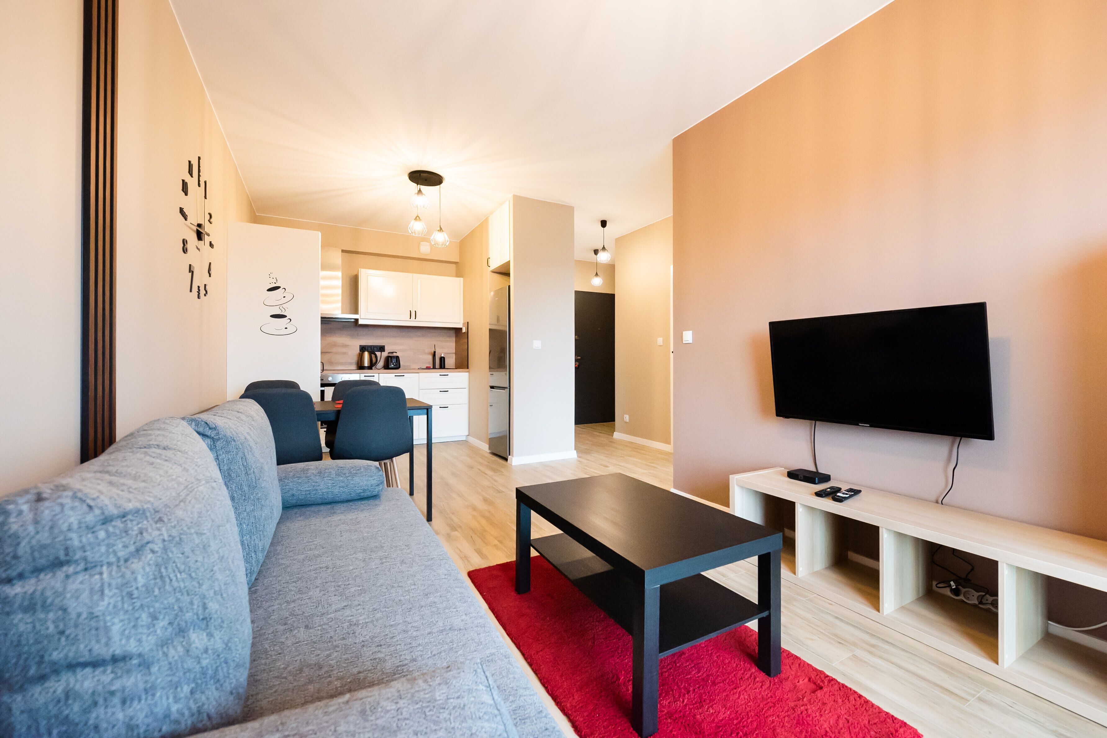 A modern living room with a sofa, a coffee table, and a TV on a stand.