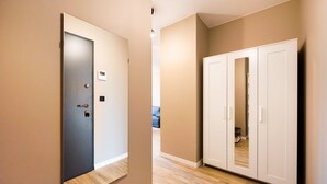 A hallway with a closed door, a wardrobe, and a light switch on the wall.