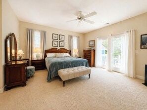 A bedroom with a bed, a bench, a dresser, a mirror, and a ceiling fan. - SHEARWATER'S NEST - Single level 3 BR Home with Private Pool, 375 yards to beach (Southern Shores)