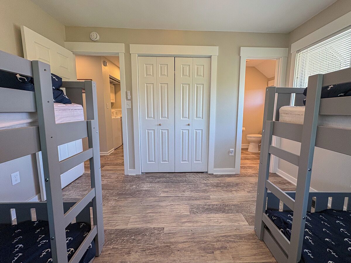 A room with bunk beds, a door, and a bathroom visible in the background.