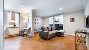 Een moderne woonkamer met een grijze bank, een eettafel met stoelen en een televisie op een meubel.