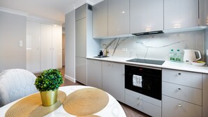 Een moderne keuken met witte kastjes, een zwarte vaatwasser en een marmeren spatwand.