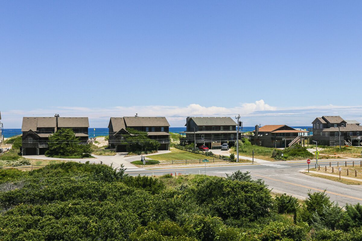 A coastal residential area with houses, a road, and a stop sign.