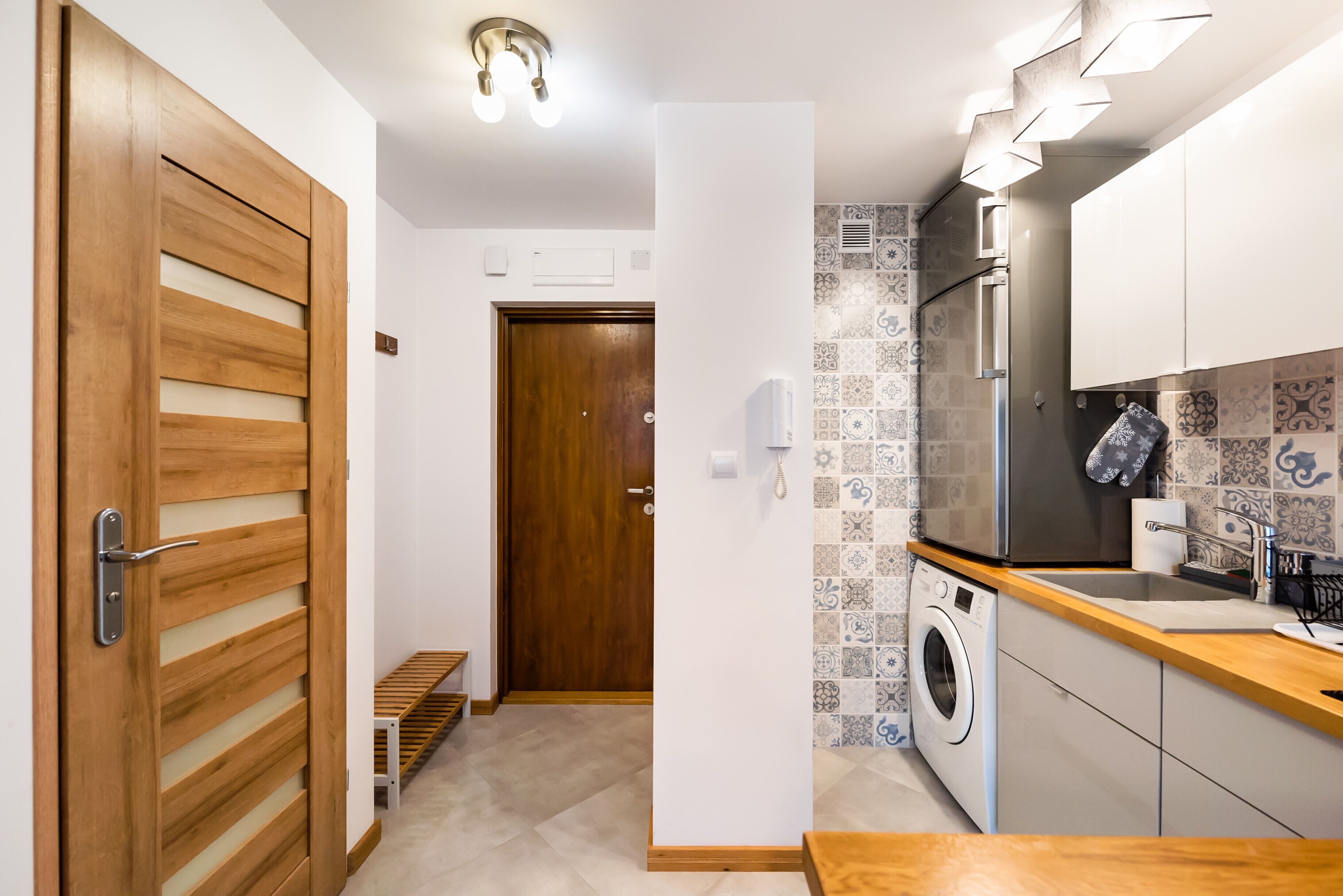A compact kitchen with a washing machine, a sink, and a wooden door.