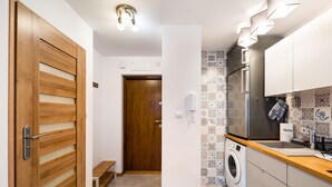 Una cocina compacta con lavadora, lavamanos y puerta de madera.