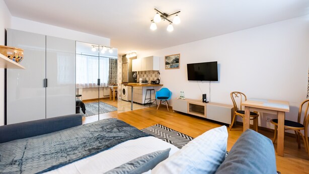 Un dormitorio moderno con una cama grande, un escritorio y una kitchenette al fondo.